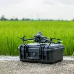Drohne auf Hartschalenkoffer vor Reisfeld