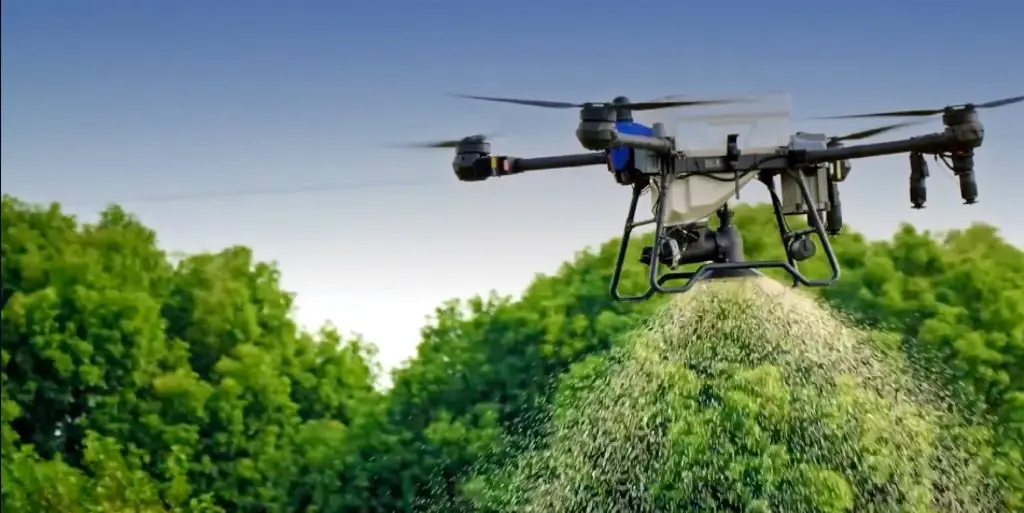 Drohne verstreut Granulat vor Bäumen