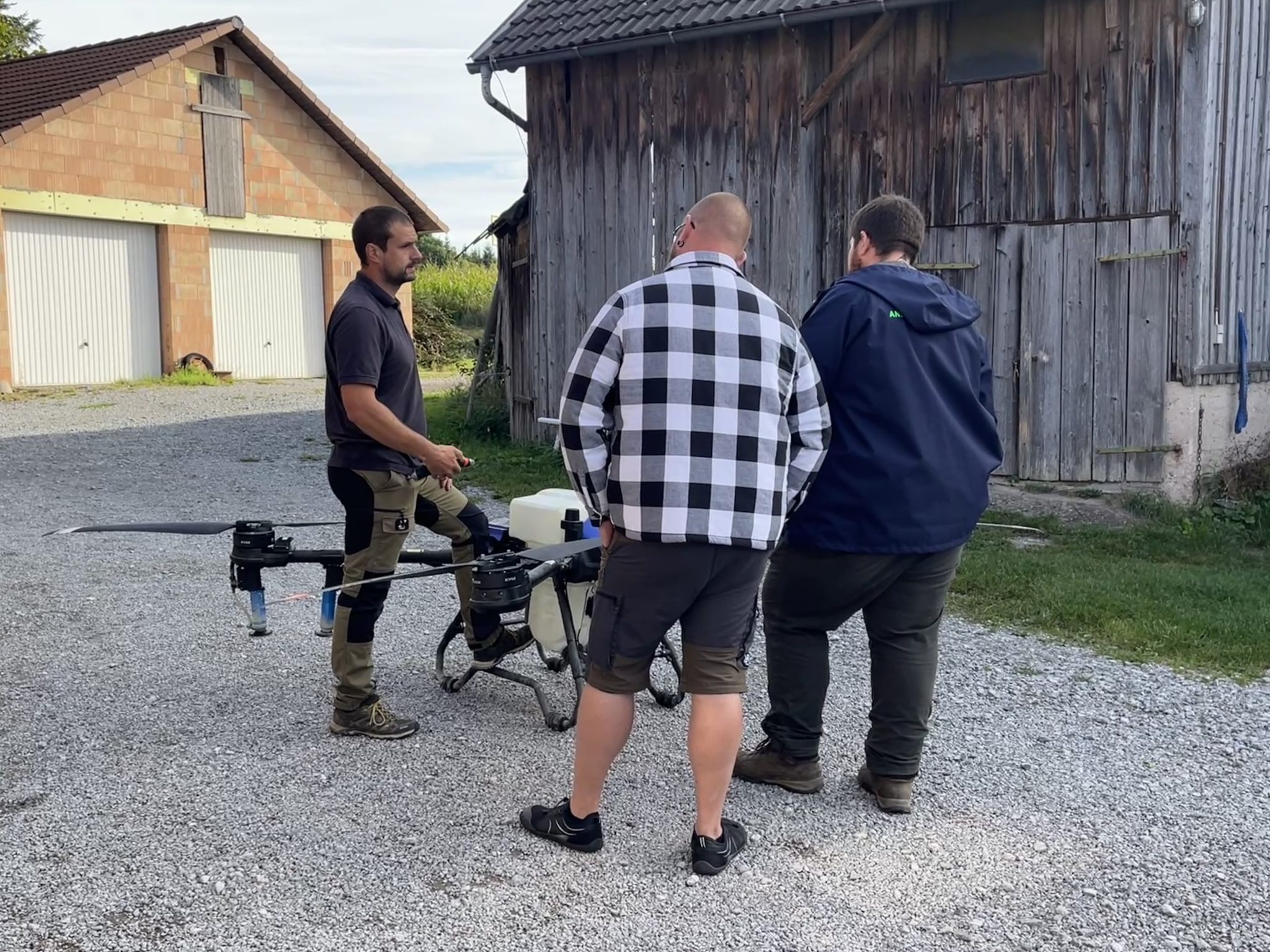 Drei Männer stehen um eine Drohne und bekommen diese erklärt.